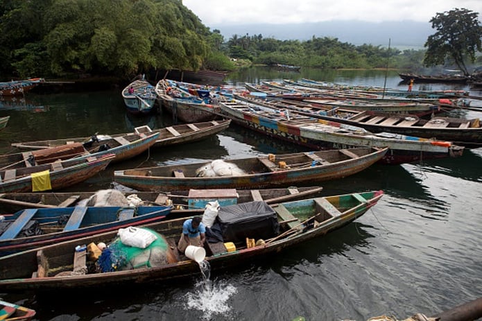 A man removes water from a fishing boat in Idenau, Cameroon. Illegal activity by foreign fishing companies has depleted fishing stocks