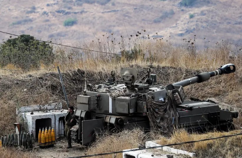 An Israeli soldier stands next to an artillery unit on the Israeli side of the Israel-Lebanon border August 6, 2021