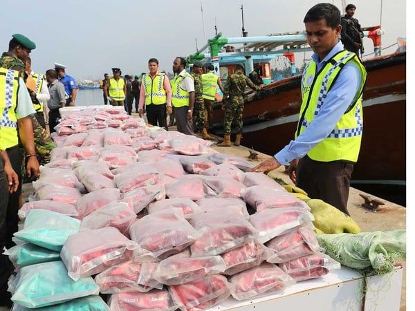 Sri Lankan police stand next to over $33 million worth of heroin and crystal methamphetamine seized from two foreign trawlers.