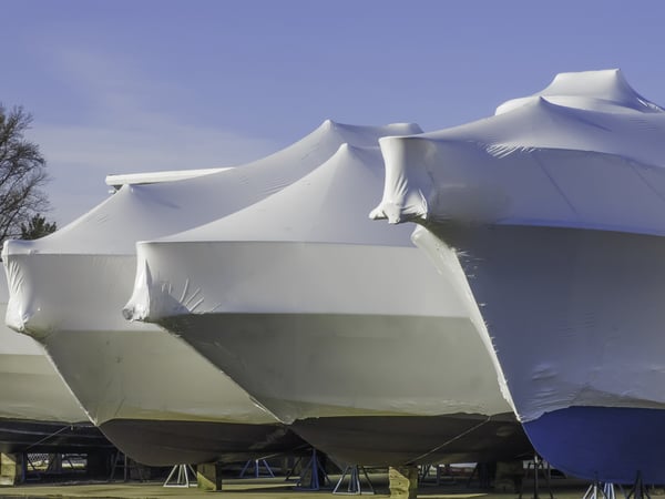 Waiting for nice weather is part of a lifestyle Bows of shrink-wrapped yachts in boatyard on a sunny morning, spring in southwestern Michigan